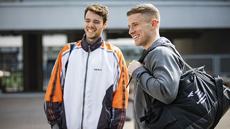 Two NCI students holding their sports bags