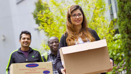 NCI student holding a cardboard box full of belongings