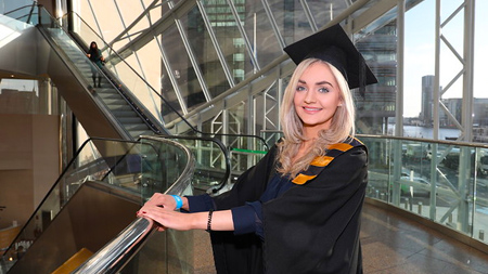 NCI student wearing a gap and gown for graduation