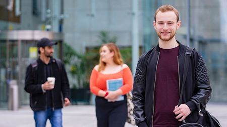 NCI student smiling at camera with classmates in background