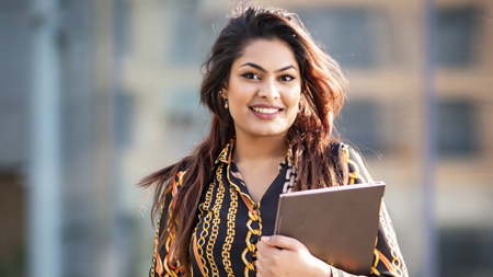 NCI Student smiling at camera holding folders