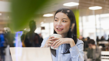 NCI student drinking from a cup in the college canteen