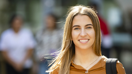 NCI apprenticeship student smiling at camera with bag strap on her shoulder