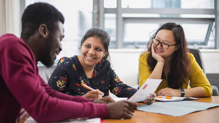 Three NCI students sitting at a table discussing notes