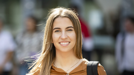 NCI student standing in courtyard on campus and smiling at camera