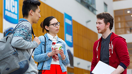 Three NCI students talking to each other in NCI atrium