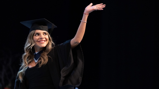 A female student walking the stage on NCI's graduation day