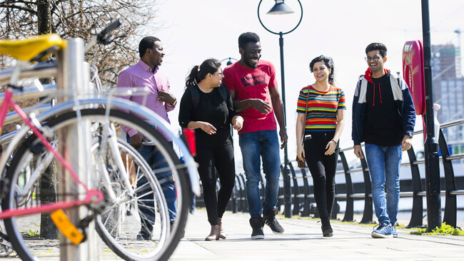 NCI students laughing and walking alongside the River Liffey