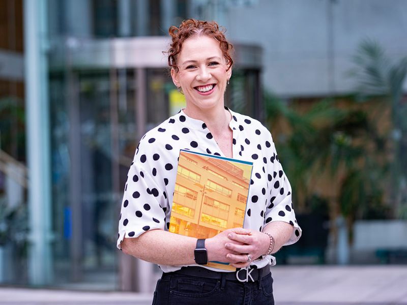 (CIPD) Certificate in Professional Human Resource Practice student holding book outside NCI entrance
