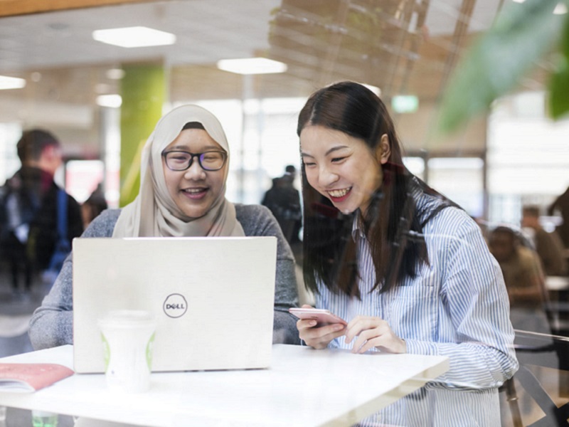 NCI students working together on a laptop in the canteen