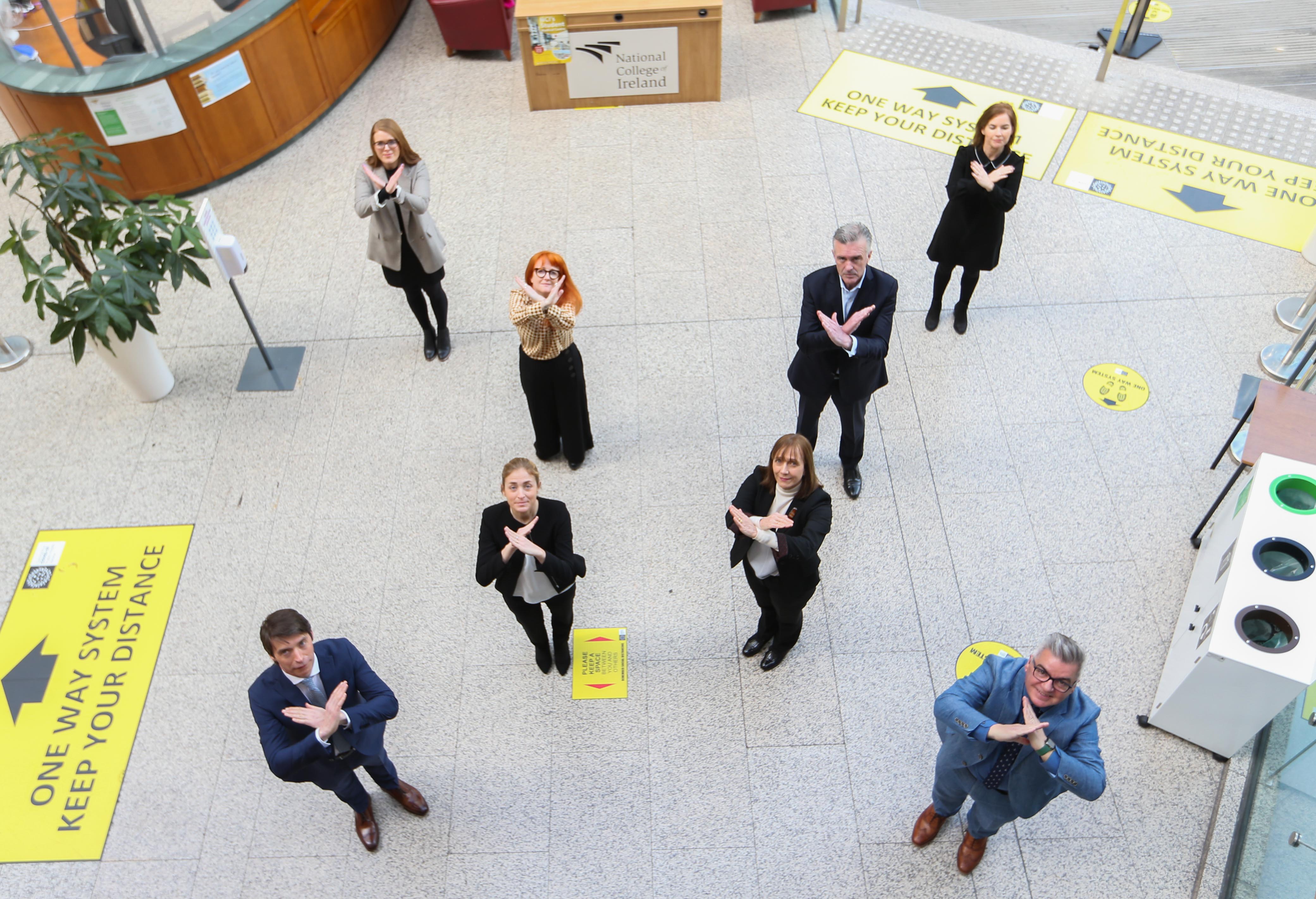 Senior staff from NCI and from Amundi Ireland standing in an X formation to symbolise Break the Bias on IWD2022