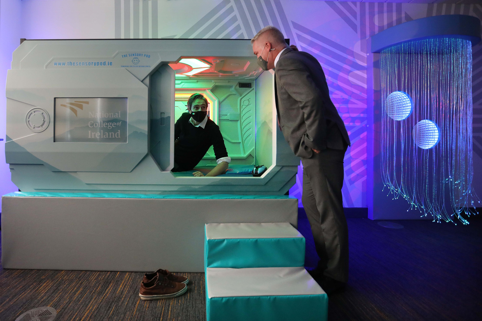 Minister Simon Harris DFHERIS inspects a sensory pod, guided by NCI's Director of Marketing Robert Ward