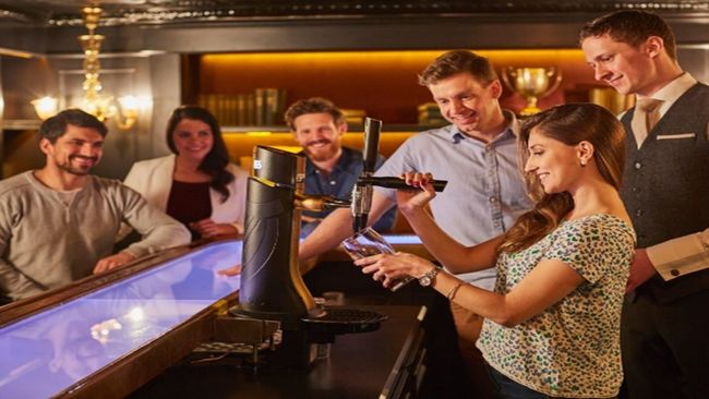 women pouring a pint of Guinness surrounded by friends