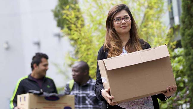 female student carrying cardboard box